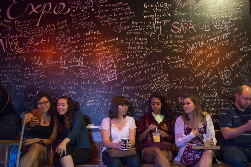 Customers sit under a chalkboard of notes and thank yous   at Expresso Expos