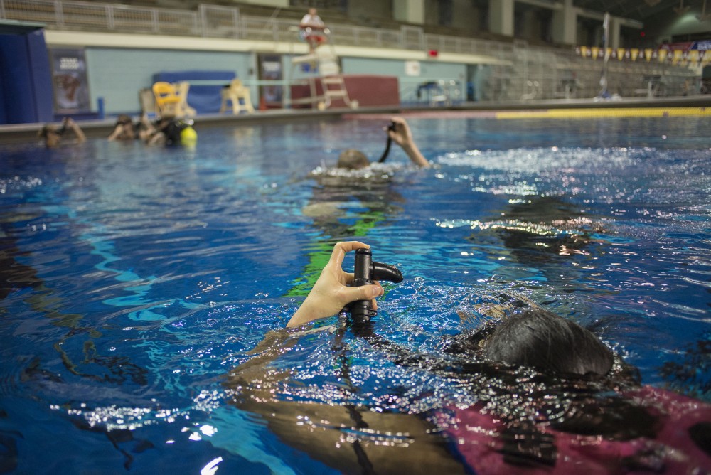 Students hold up there buoyancy compensate devices above the surface of the water on Sept. 21, 2016, at the University Aquatic Center. The BCD device allows divers to stay buoyant underwater as well as on the surface.  