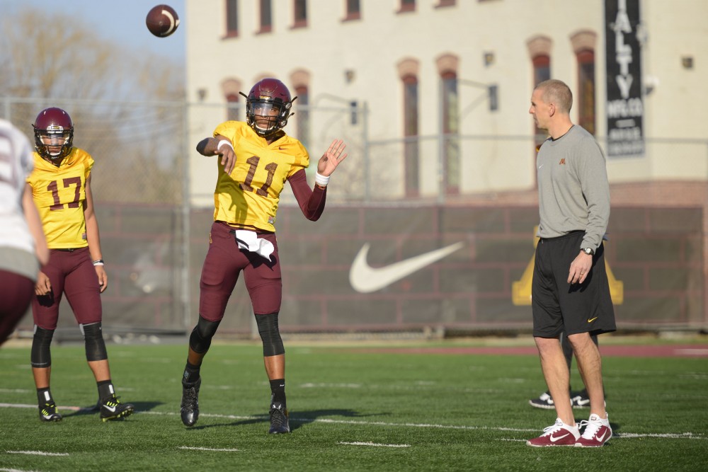 Offensive coordinator Jay Johnson, right, watches sophomore quarterback Demry Croft throw a ball in a practice on March 10, 2016.