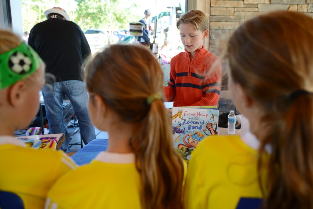 A group of girls look on as Frank Kamish displays his book Frank Henry and the Zooband Band at Elmcrest Park in Ramsey on Saturday. Frank, a fifth grader at Lake Harriet elementary, illustrated the book, which he created alongside his father, Paul, and his uncle, David.