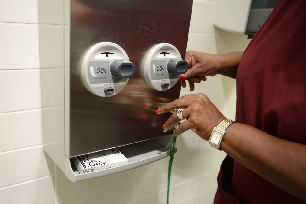 Facilities Management employee Sandra Johnson refills a tampon and pad dispenser in the Cancer and Cardiovascular Research Building on Oct. 11, 2016. MSA has been working with Facilities Management to increase the availability of these supplies across campus, including putting dispensers in gender-neutral bathrooms.
