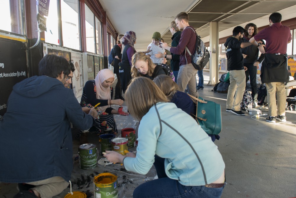 Students gather to repaint the Muslim Students Associations panel inside the Washington Avenue Bridge on Friday. The students showed their support after the panel was vandalized with the word ISIS.