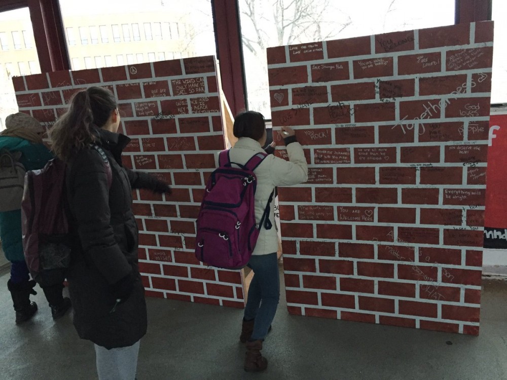 Students sign a fake brick wall that was placed in front of the College Republicans at the University of Minnesotas panels on Washington Avenue bridge on Monday, Dec. 12, 2016.
