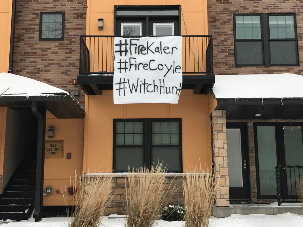 A sign that reads #FireKaler #FireCoyle #WitchHunt hangs from an apartments balcony across the street from Gibson-Nagurski Football Complex on Friday, Dec. 16, 2016.
