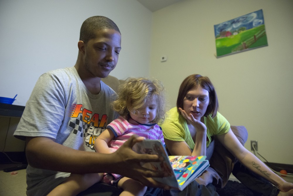 Vincent Grear and his fiancee Ashley Crook read to their daughter Charlotte in the Glendale Community Townhomes on Thursday, Feb. 9, 2017. The family recently moved to Glendale after living on Hennepin Avenue downtown. Grear said the first few times he heard gunshots he would bolt awake, but then learned to sleep through it. Its a lot quieter here, Grear said. 