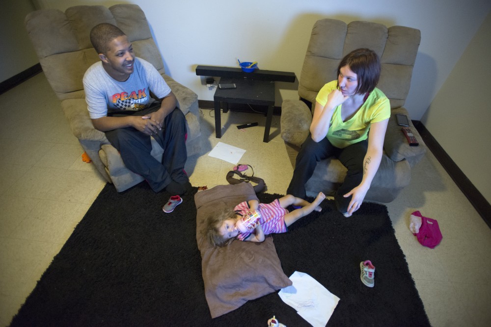 Vincent Grear talks to his fiancee Ashley Crook while their nearly two-year-old daughter Charlotte lays on the floor on Thursday, Feb. 9, 2017. The family moved into the townhomes in December but could be displaced by redevelopment. 