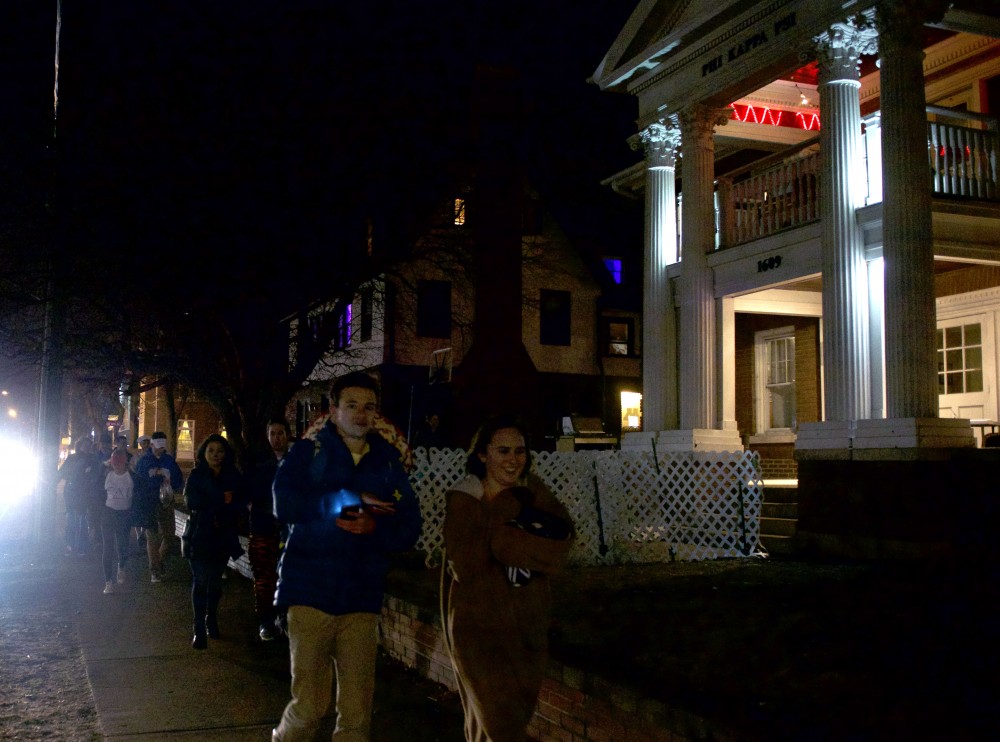 A large group walks past fraternities on Fraternity Row on March 10, 2017.