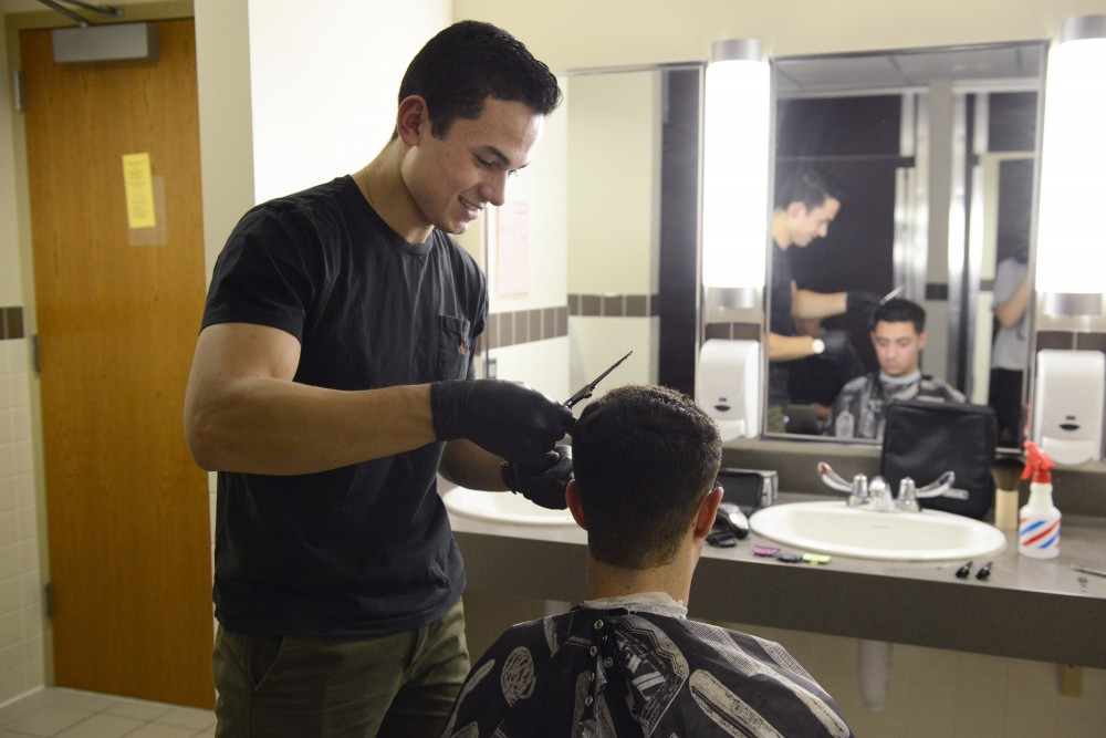 Adam Mikell works on a haircut for one of his frequent customers, Adi Mizrahi, on Thursday, March 6, 2017 in 17th Avenue Residence Hall. 