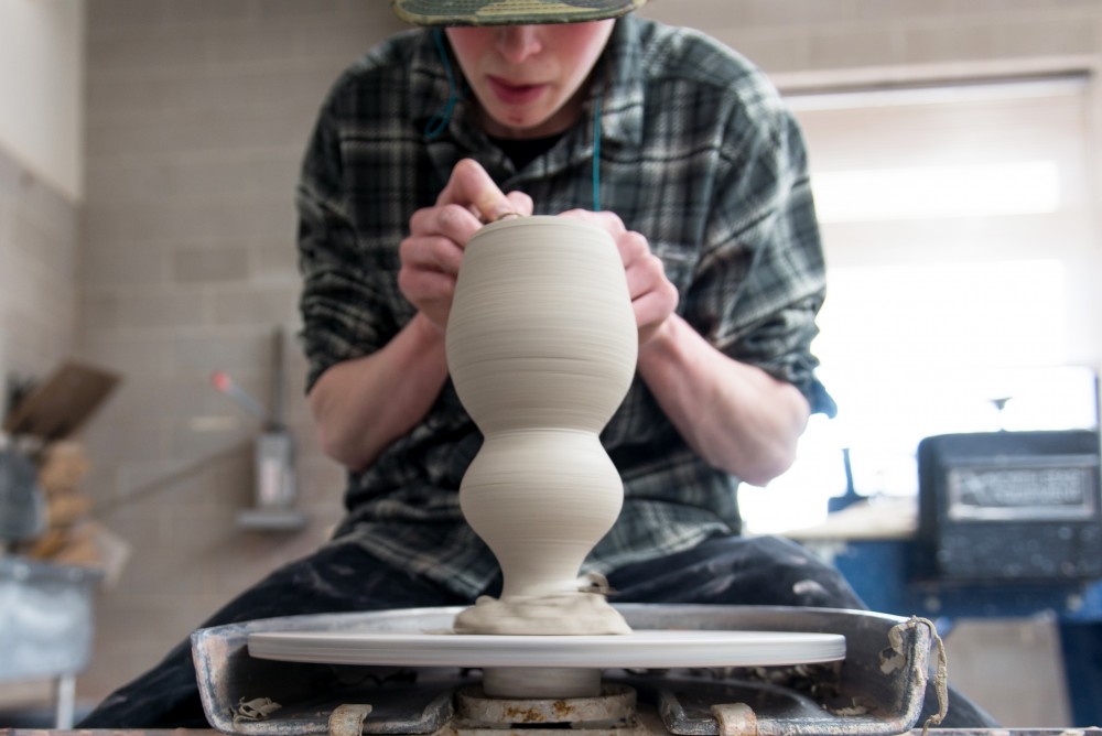 Gabe Renz carefully trims a bottom on his ceramic vessel at Regis Center for Art on April 7, 2017.