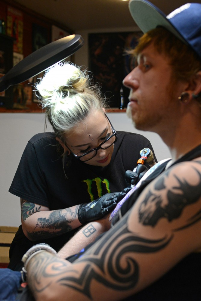 Tattoo artist Lucy Austad works on a piece on Chris Wilkings arm at Dinkytown Tattoo. 