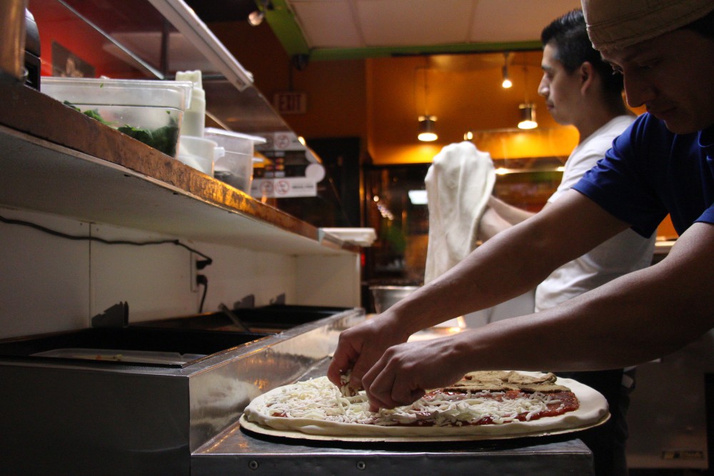 Mesa Pizza employees prepare pizza-by-the-slice at the restaurant.