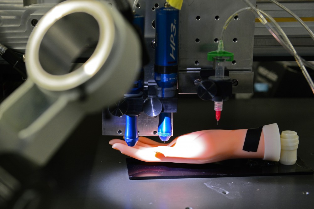 A model hand sits under a 3D printing device in a lab in the Mechanical Engineering building on May 23, 2017. Michael McAplines lab has designed a method of 3D printing that could allow for printing on human skin.