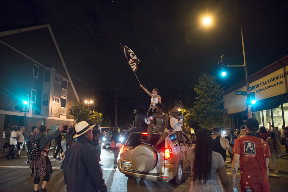 Mia Holmes stands on top of a car while waving a Black Lives Matter flag in St. Paul on Friday, June 16.
