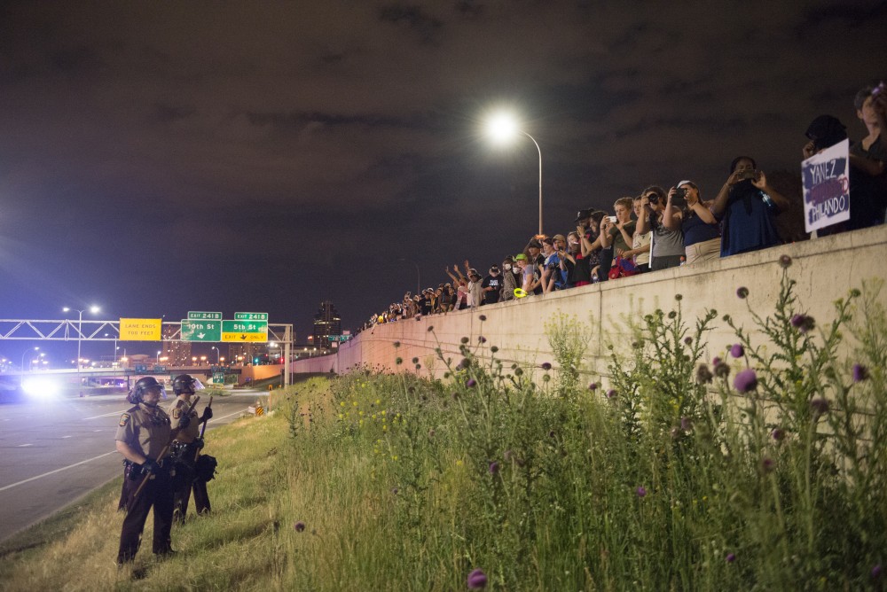 Protesters overlook law enforcement officers from an exit ramp in St. Paul on Friday, June 16.