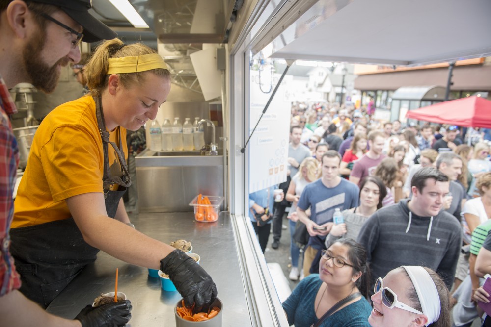 Haley Fritz, co-owner of Dough Dough Dessert Food Truck, hands a customer spoons for their cookies by the spoonful at the Uptown Food Truck Festival on Sunday, June 25, 2017. The truck had customers waiting for over 40 minutes to get their cookie dough and sold 2800 scoops throughout the day.