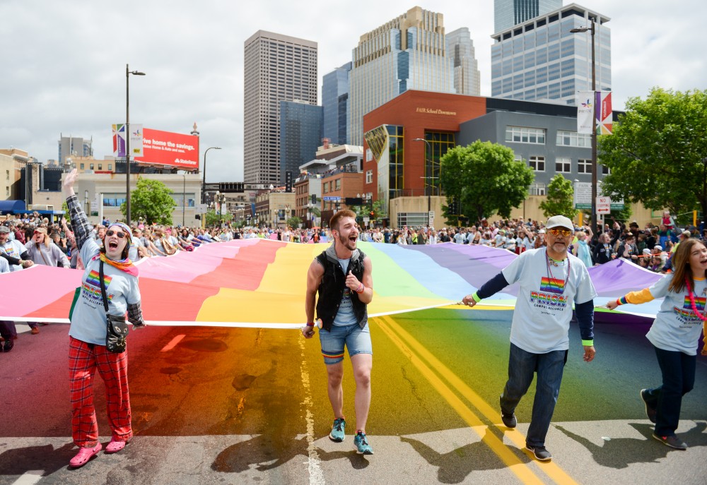 Mitch Vosejpka, center, holds a rainbow flag during the Twin Cities pride parade. 