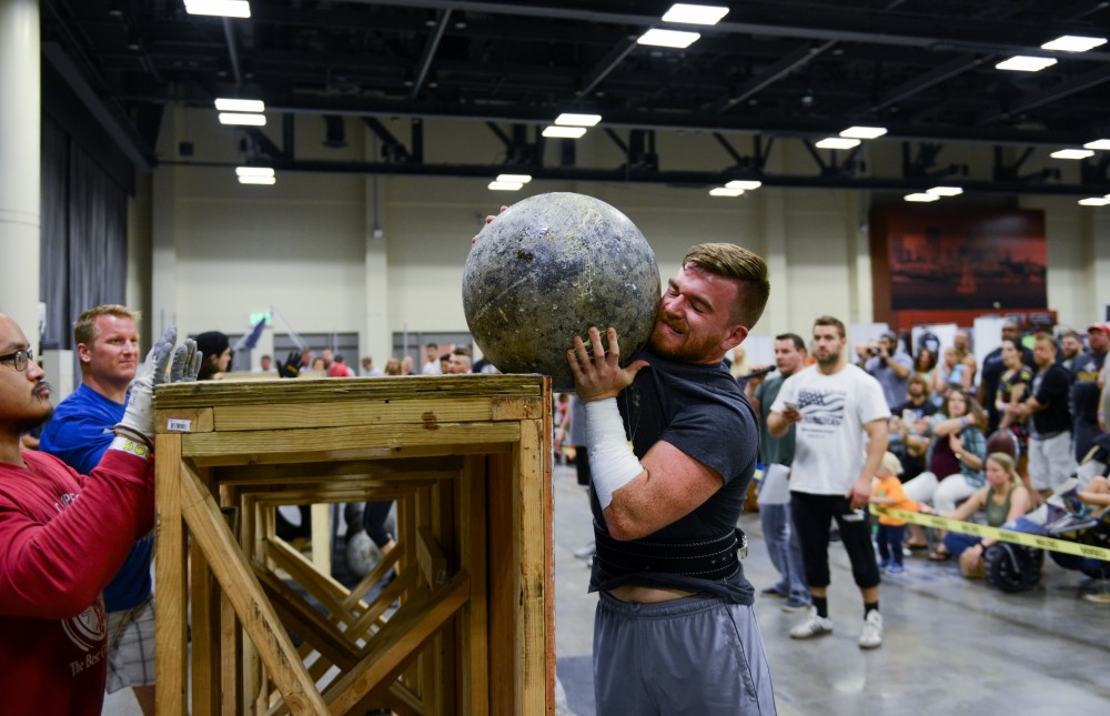 Andrew Laureijs lifts a concrete ball on top of a platform during the USS Minnesota show of strength strongman competition.
