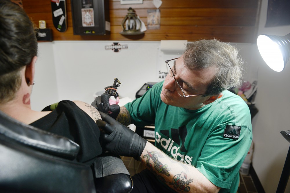 Greg Lombardi works on a tattoo on Nik Bloomfields arm at Dinkytown Tattoo on June 3, 2017.