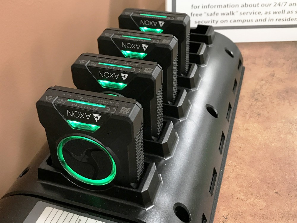 Body cameras sit in a charging cradle.
