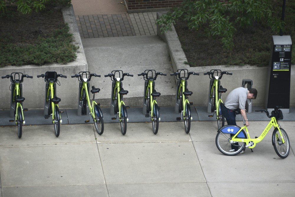 A commuter adjusts the seat on a Nice Ride bike on Friday, July 7 outside of Keller Hall on East Bank.