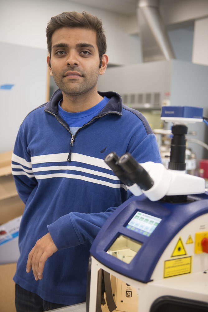PhD student Kanav Khosla poses for a portrait next to a gold nanotechnology laser on Thursday, July 13 in Nils Hasselmo Hall. Khosla is the lead author on a research paper about cryopreservation of zebrafish embryos using the technology.