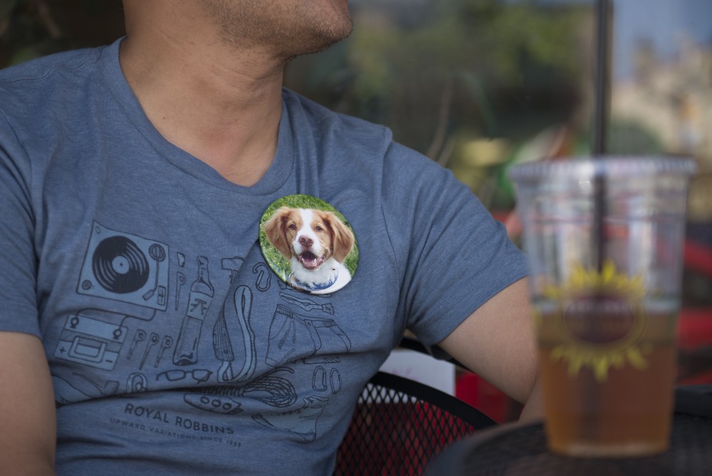 Louie Tran sits outside Espresso Royal Coffee Shop with a button of his beloved well known dog Chip that recently passed away. 