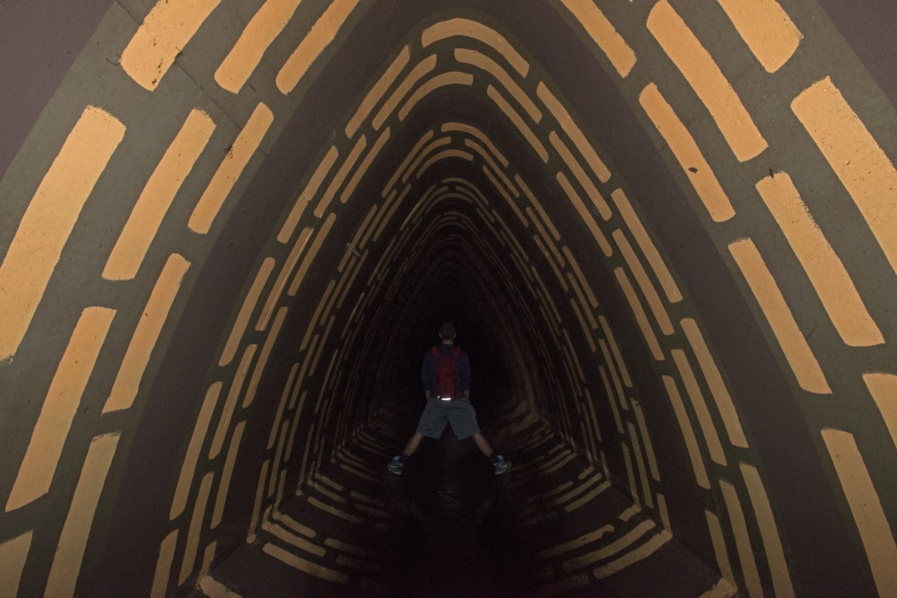 An explorer stands in portion of an underground passageway painted by other explorers.