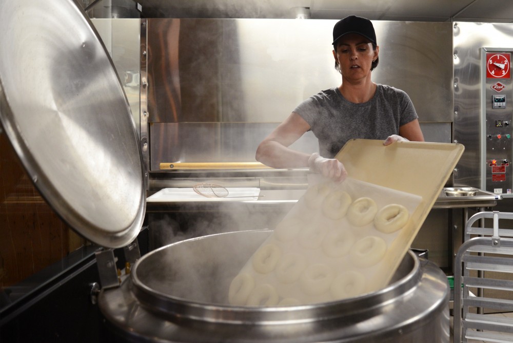 Jen Lloyd slides a pan of doughy bagels into a mixed vat of water with malt barley syrup at Rise Bagel Co. in Minneapolis on Tuesday. 