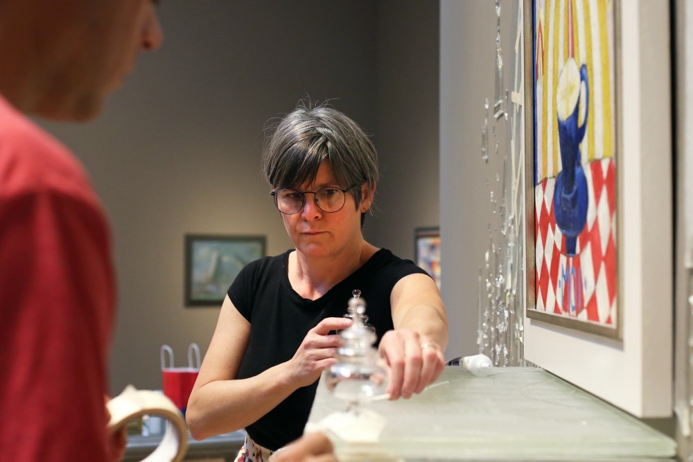 Artist Beth Lipman puts the finishing touches on her new work in Weisman Art Museum on Friday, Sept. 29.  The glass sculptures height reaches more than halfway up the museums wall.