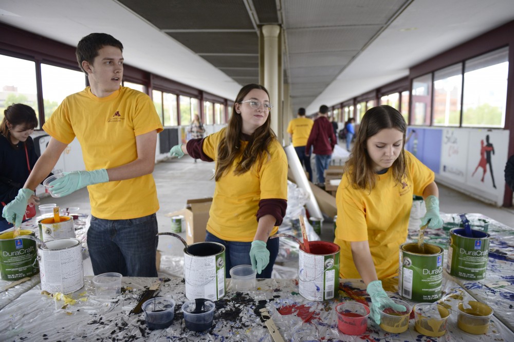 Kirsten Price, Mariaka Lumholdt, and Jack Sazama volunteer during Paint the Bridge on Washington Avenue bridge on Friday. 