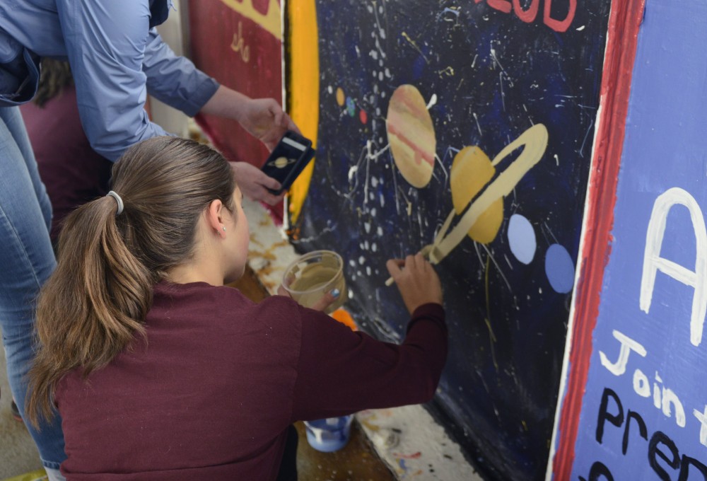 Dina Carpenter-Graffy and Meg Foster work on the Astronomy clubs wall during paint the bridge on Friday on Washington Avenue bridge.
