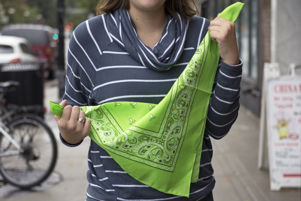 Project Lead Emily OConnell holds up a green bandana outside of Espresso Royale on Friday, the symbol the Bandana Project has chosen to represent students who are trained to help others deal with mental health issues around campus. 