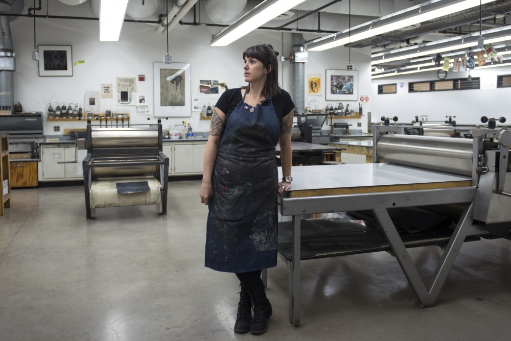 Professor and printmaker Edie Overturf stands next to a printing press she uses to create most of her work. Edie teaches a variety of print making and drawing classes at the University.
