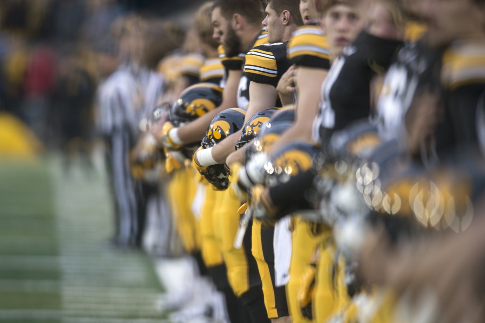 The Hawkeyes line the edge of the field and remove their helmets during the National Anthem prior to playing the Gophers on Saturday, Oct. 28.