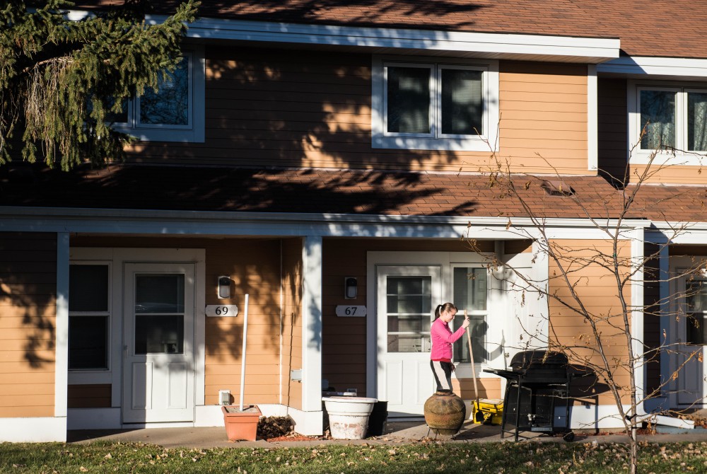 Jackie Smith, 26, burns leaves outside of her apartment just north of the West Bank campus on Tuesday, Nov. 28. Her building is part of a cluster of townhouses that will be undergoing rehabilitation in 2018.