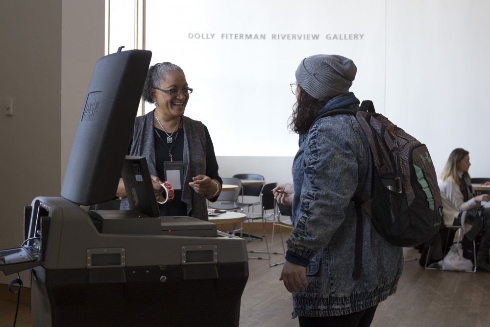 Election judge Mikki Murray speaks with sophomore Melissa Riepe at Weisman Art Museum on Tuesday, Nov. 7 in Minneapolis. Riepe voted for Raymond Dehn, saying she liked his platform page and he seemed the most educated. Murray has been a volunteer election judge since Obamas first presidential election.