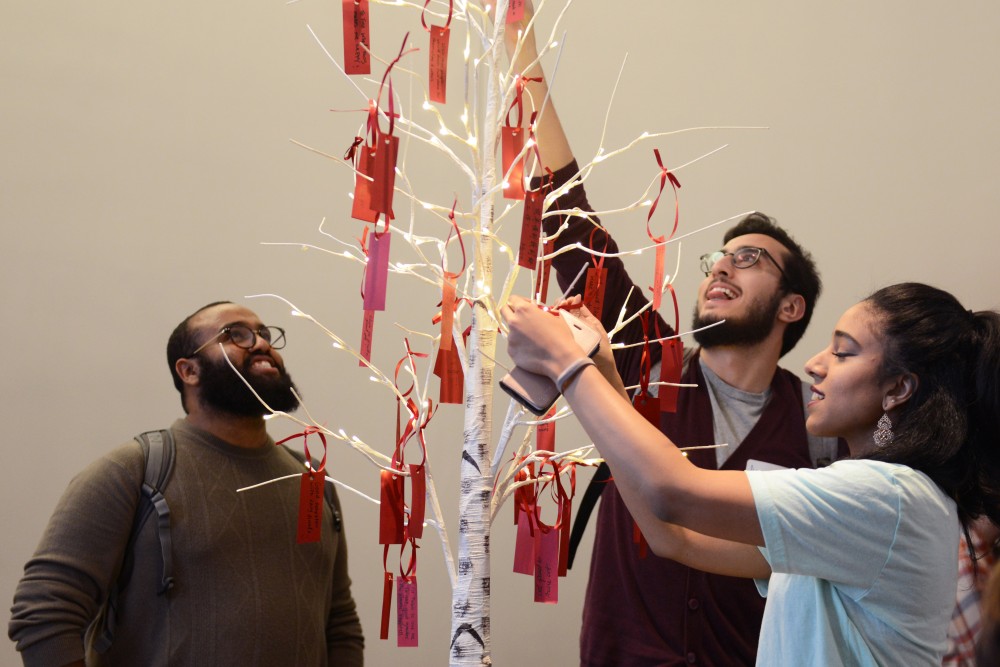 Event goers place their pieces of paper on a tree at Weisman Art Museum Friday, Nov. 3.
