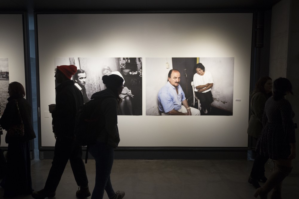 Viewers of Gustavo Germanos work roam the gallery at the exhibit opening at Regis East on West Bank on Friday, Nov. 10. Germanos exhibition entitled Absences showcases people detained or murdered by civic-military dictatorships in Argentina, Uruguay and Brazil.