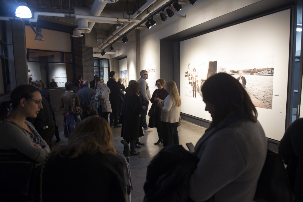 Viewers of Gustavo Germanos work explore the gallery at the exhibit opening at Regis East on West Bank on Friday, Nov. 10. Germanos exhibition entitled Absences showcases people detained or murdered by civic-military dictatorships in Argentina, Uruguay and Brazil.