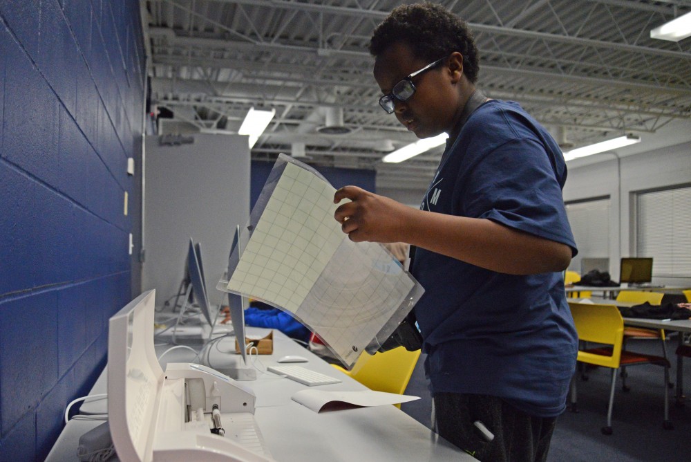 Mahad Ahmed removes a vinyl sheet from a Cameo cutting machine at the new teen tech center at the Brian Coyle Center in Minneapolis on Tuesday, Nov. 21.