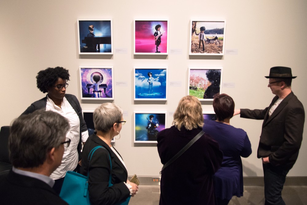 Attendees of the preview party for the Prince from Minneapolis exhibition look on photos created by Troy Gua at the Weisman Art Muesum on Friday, Dec. 8. Gua created miniature models of Prince and photographed them in settings iconic to the artist. 