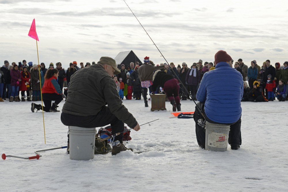 Two men ice fish while watching the artist group Mixed Precipitation perform Tonya and Nancy: The Opera during the Art Shanty Projects event on Lake Harriet in Minneapolis on Saturday, Jan. 20.