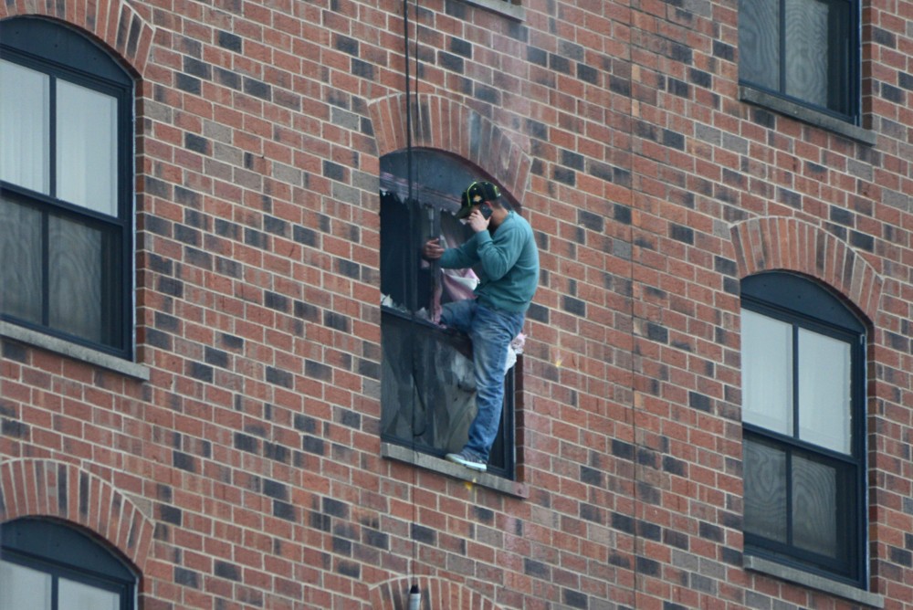 Rashad Bowman, 43, stands on the ledge of the sixth-floor window at 1:15 p.m. Tuesday after two loud explosions were heard at 1:09 p.m.