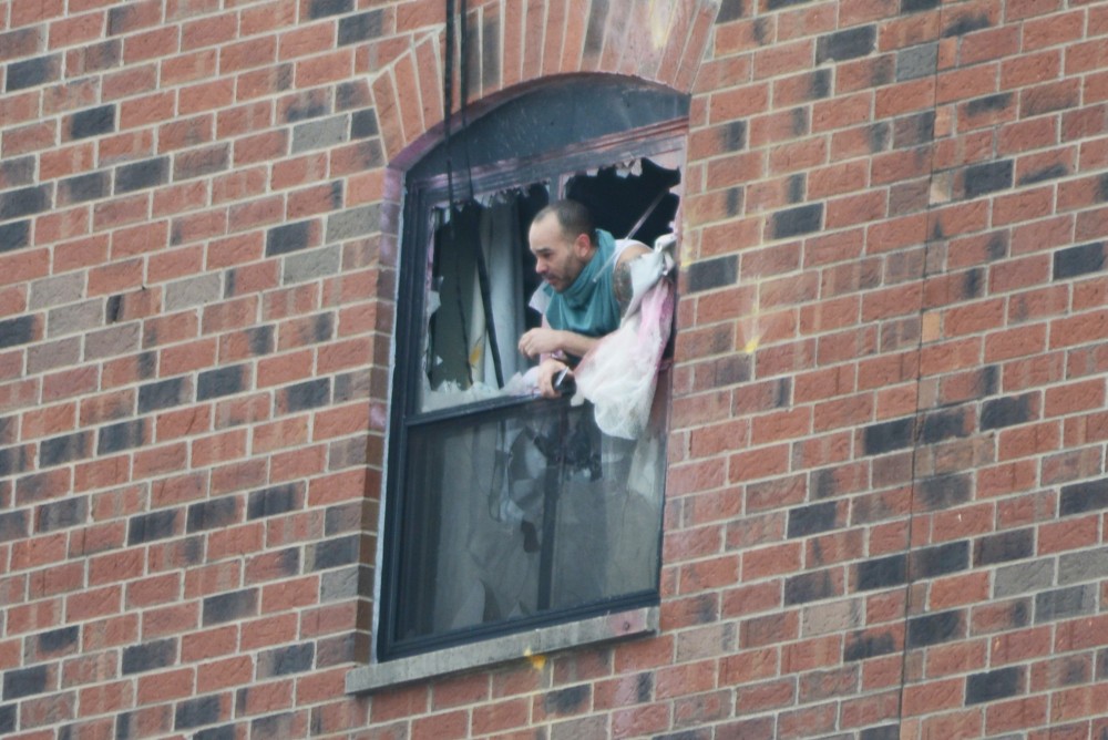 A man pokes his head out the sixth floor window at 11:40 a.m. after police fired gas into a sixth floor room at the Graduate Hotel. Police say the suspect is in the room and believe he is the only person in the room.
