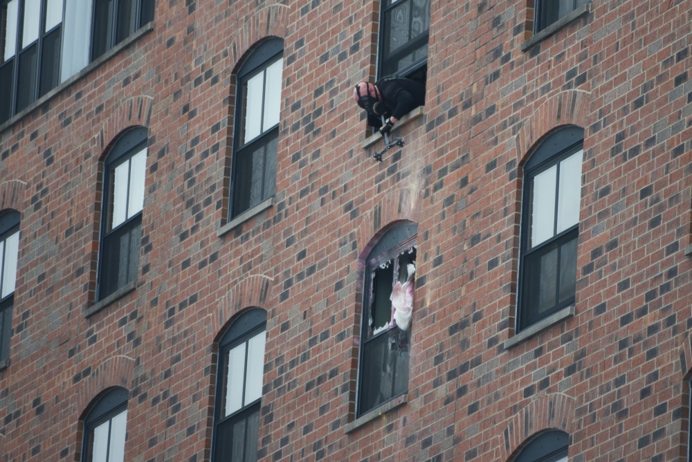 An officer looks down at the sixth floor window of the room at the Graduate Hotel that the suspect is in. Police believe he is the only person in the room and have fired gas into it.