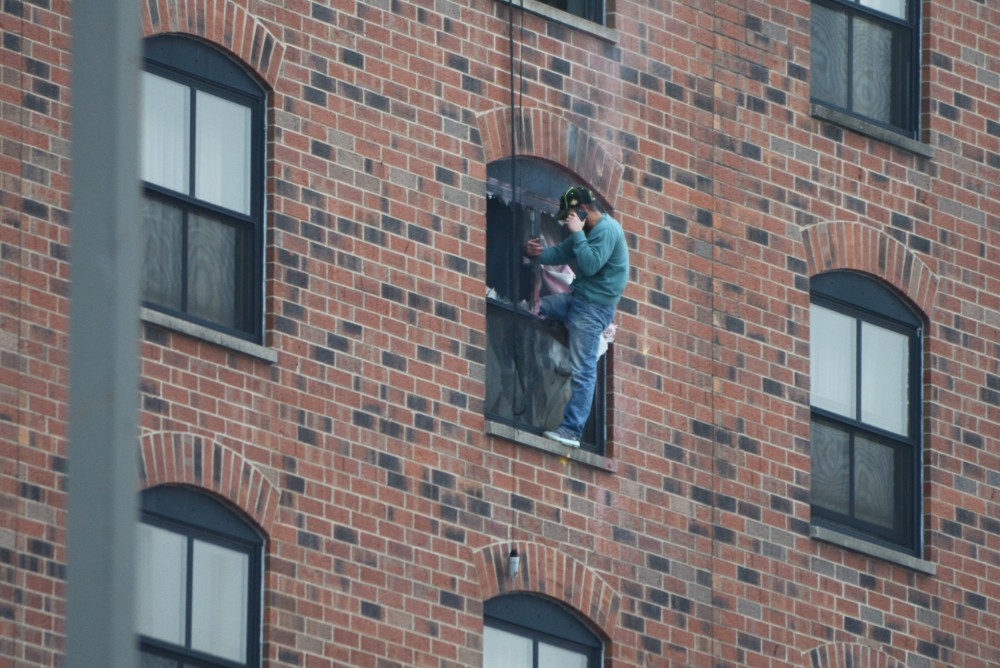 Rashad Bowman sits on the ledge of the sixth-floor window at 1:15 p.m. after two loud explosions were heard at 1:09 p.m. on Tuesday.