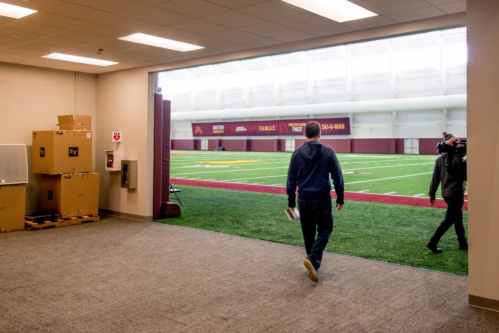 Visitors and media cross the threshold onto the new football practice filed in Athletes Village on Saturday, Feb 10.