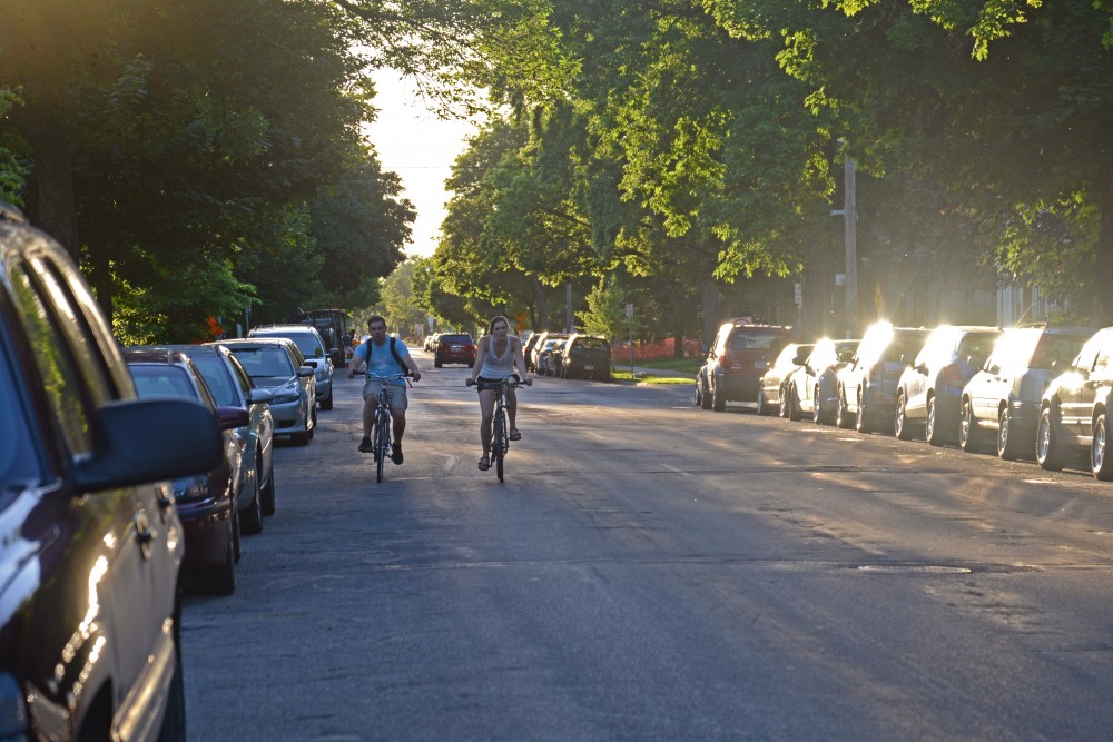 Bikers ride beside crowded parking on both sides of Eighth Street Southeast in Minneapolis on June 6, 2017.