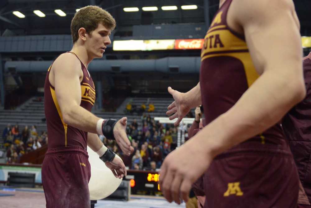 Luke Aldrich high-fives a teammate after competing on the pommel horse on Sunday, March 18.