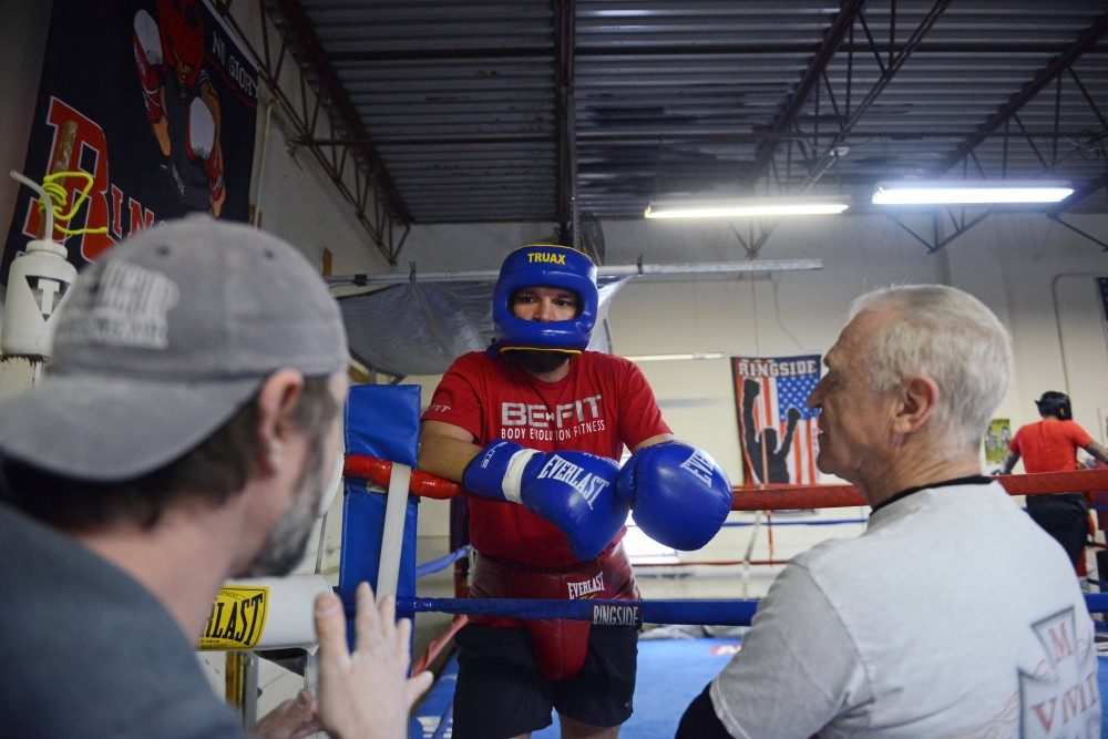 Boxer Caleb Traux, center talks to his coaches in the break of a training practice on Tuesday, March, 20.